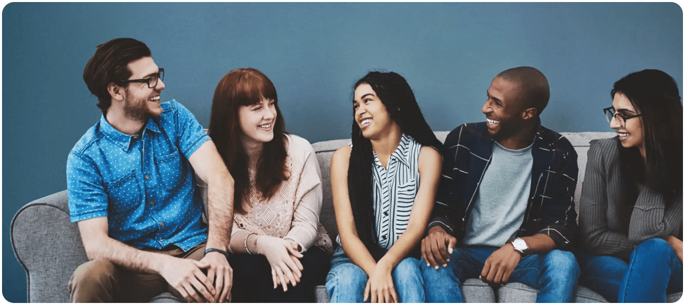 A group of young adults sitting on a couch having a conversation